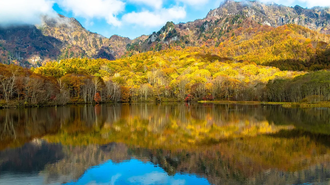 紅葉した戸隠連峰のふもとの林が、鏡池の水面に映っている