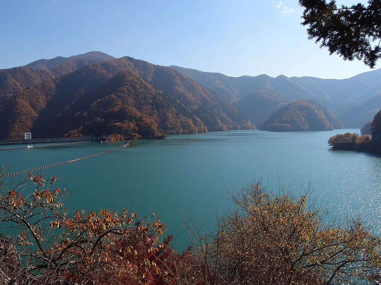 紅葉した山々に囲まれた青緑色の奥多摩湖