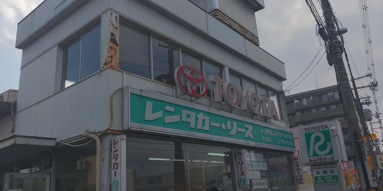 トヨタレンタリースの店舗の外観。緑の看板に「レンタカー・リース」とある