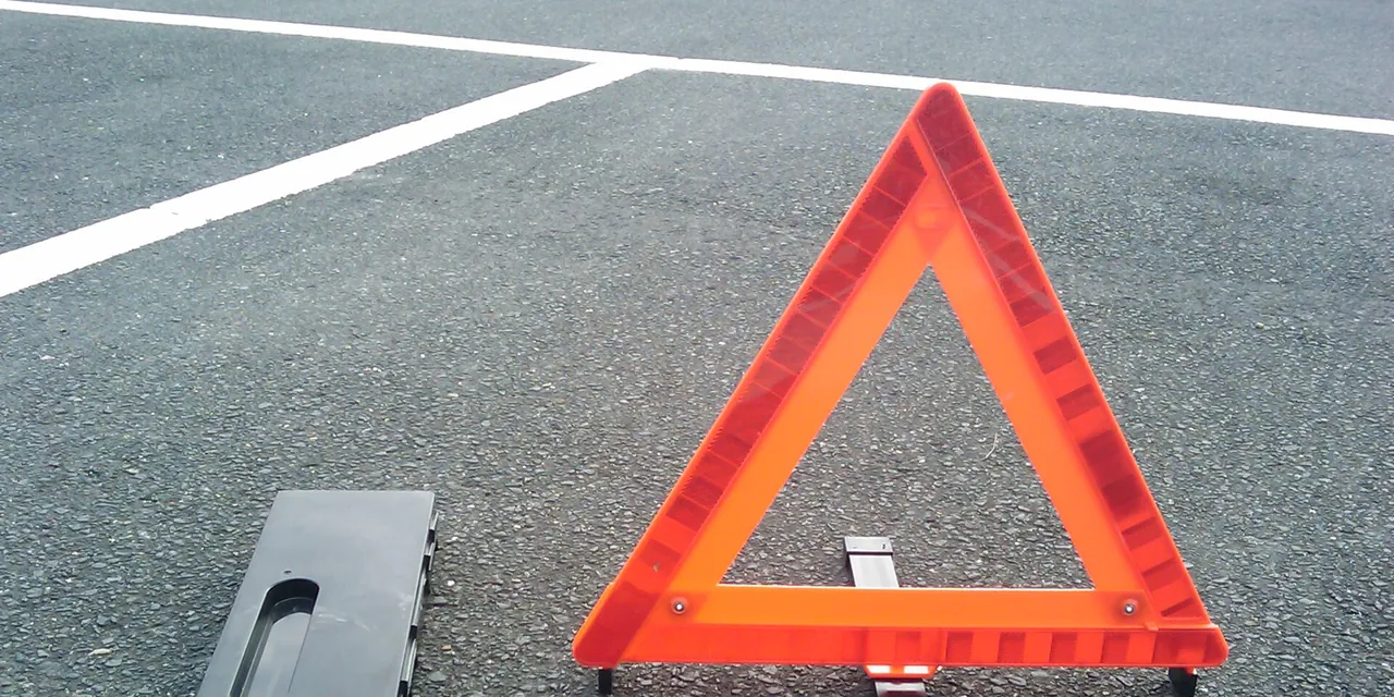 舗装された駐車場に立てた三角表示板と、その収納ケース