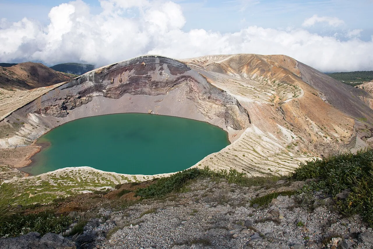 青緑色の水をたたえた蔵王の火口湖「お釜」と、周りを囲む火口壁